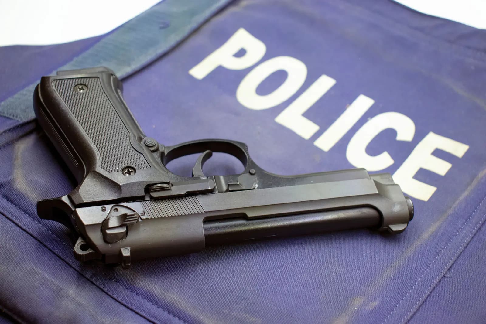 Arme de service posée sur un gilet pare-balles floqué POLICE