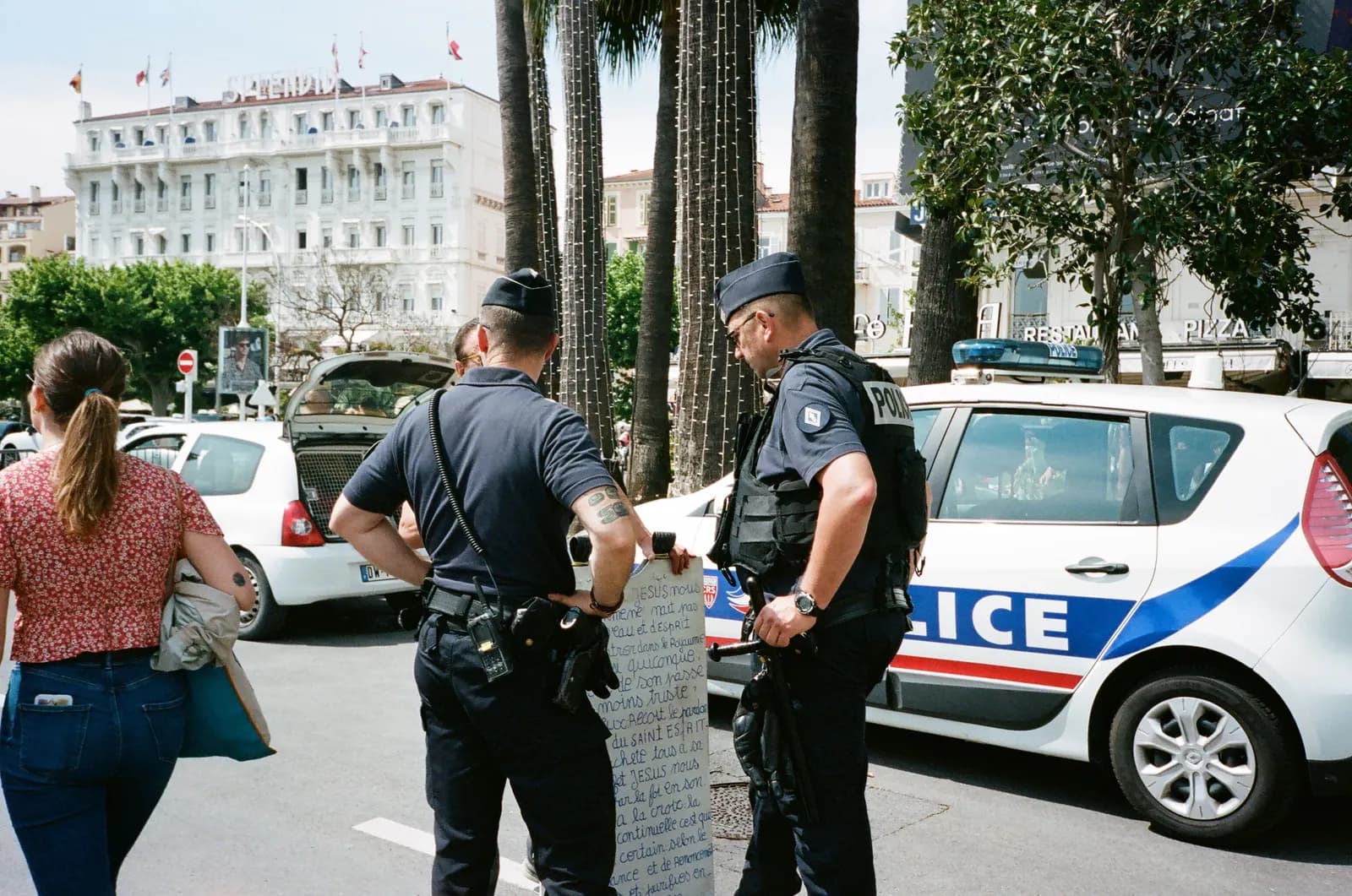 Deux policiers en tenue procèdent à un contrôle en centre-ville, véhicule sérigraphié en arrière-plan