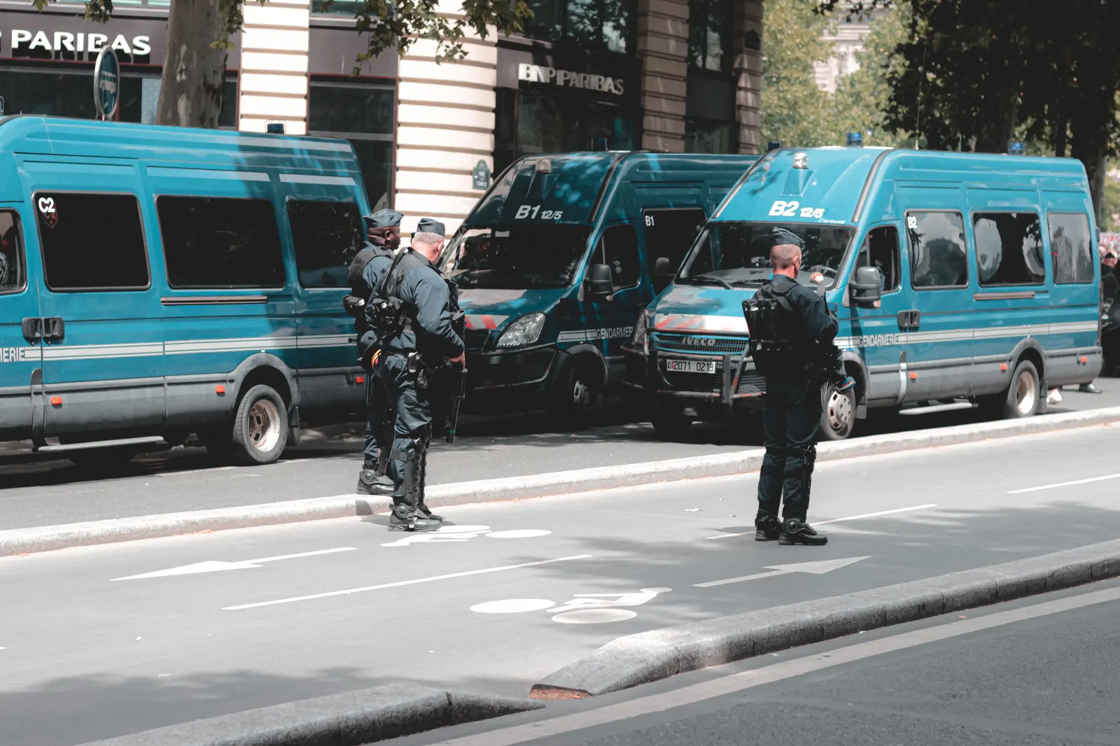 Fourgons de gendarmerie mobile alignés le long d’un boulevard parisien, deux gendarmes en faction