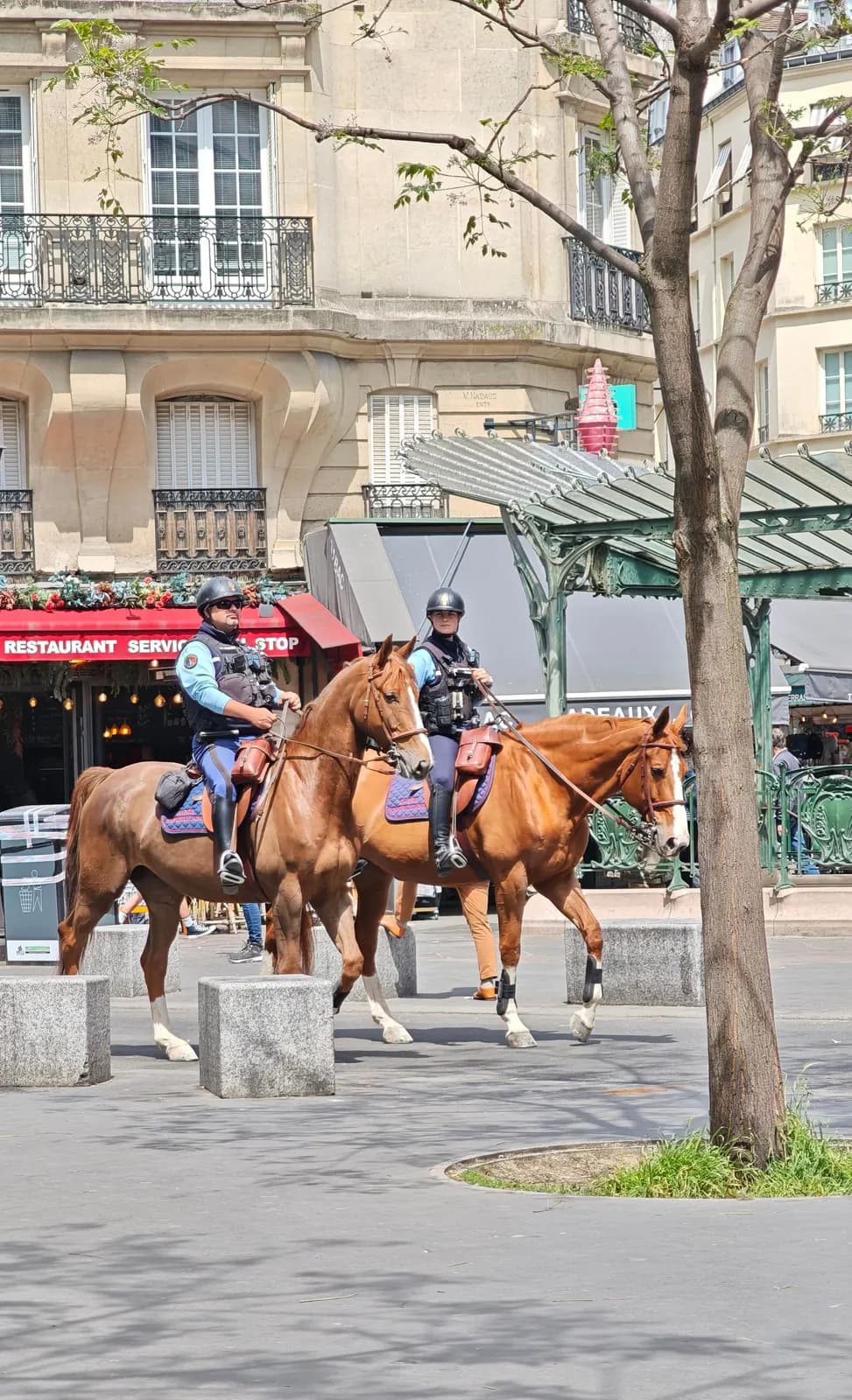 Deux gendarmes à cheval en patrouille près d’une bouche de métro parisienne